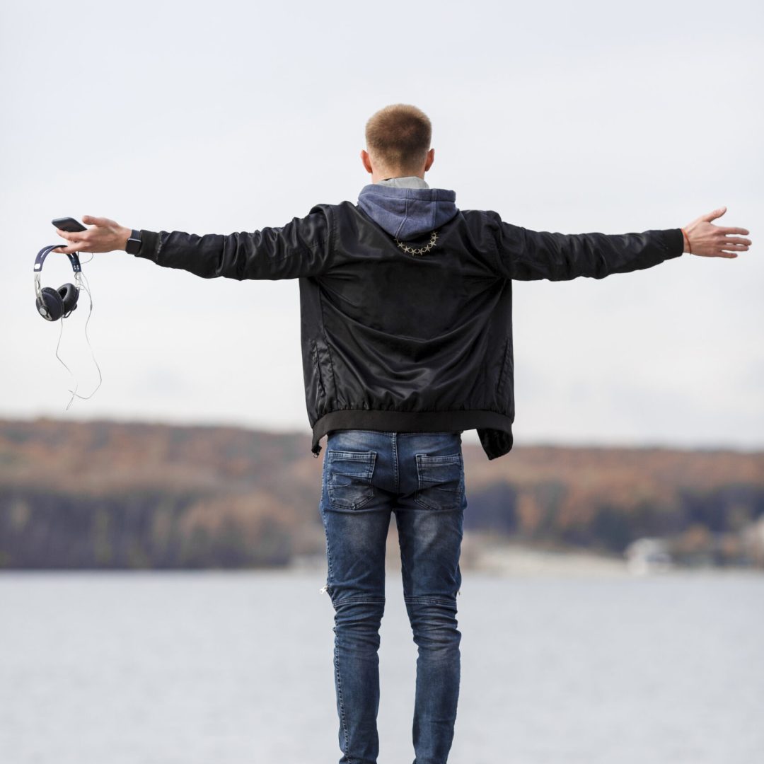 back-view-man-holding-his-headphones-while-enjoying-view